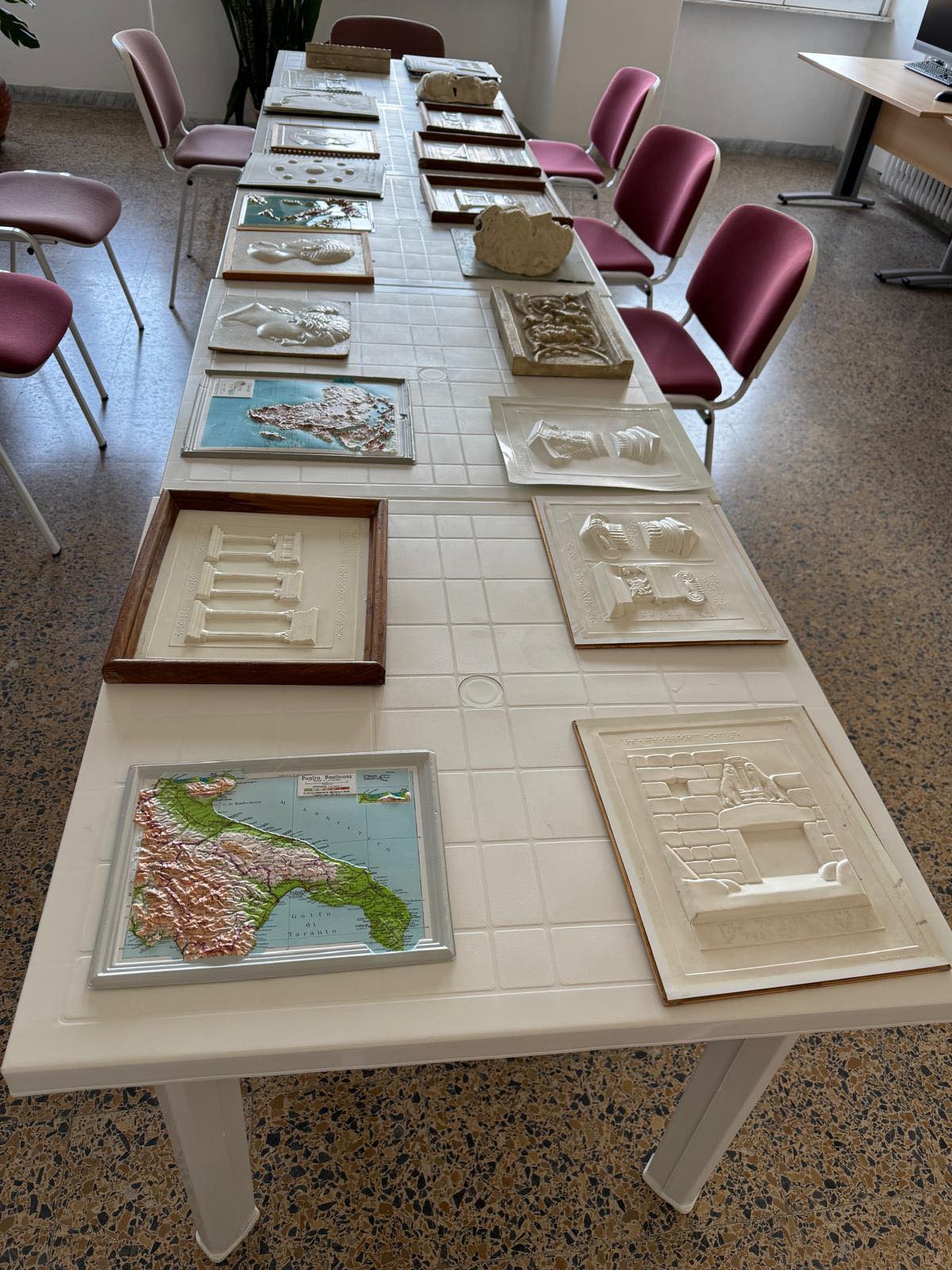 Foto di materiali vari adatti per essere esplorati tramite tatto. I quadretti riportano mappe geografiche, figure architettoniche, profili di statue, tutti in bassorilievo